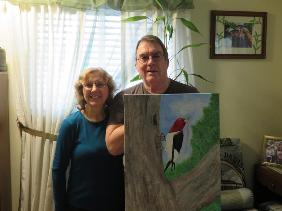 Dr Thomas Smith and His wife Sue displaying their commissioned "Red Headed Woodpecker" artwork by Juda Myers.